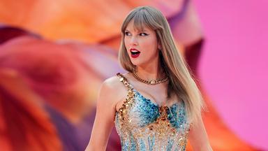 Taylor Swift in einem glitzernden Bühnenoutfit vor farbenfrohem Hintergrund während eines Auftritts ihrer Eras Tour 2024 im Wembley-Stadion in London.