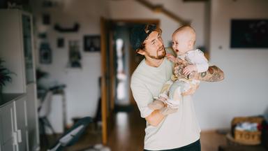 Daniel hält sein weinendes Baby auf dem Arm.
