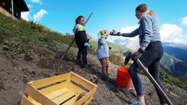Eine Frau mit zwei kleinen Kinder bei der Arbeit im Kartoffelacker