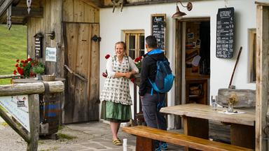Ein Mann und eine Frau vor einer Berghütte.