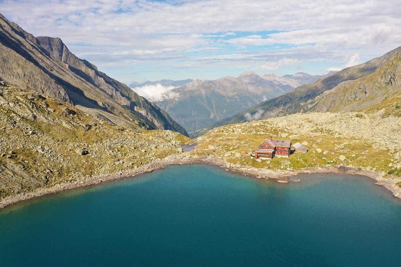 Ein rotes Haus an einem See in einem Gebirge