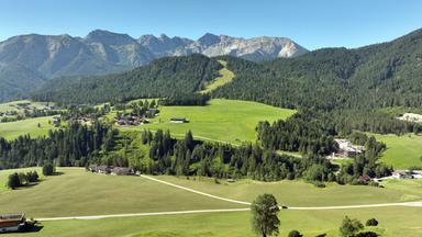 Panoramablick auf das Dorf Steinberg am Rofan, umgeben von üppigen grünen Wiesen und der majestätischen Bergkette des Rofans.