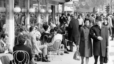 Historisches schwarz-weiß-Bild von Spaziergängern und Café-Gästen auf dem Berliner Kudamm.