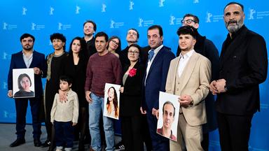 Gruppenbild der afghanischen Schauspieler des Films No Good Men auf der Berlinale, die Fotos von den Kollegen, die nicht dabei sein können, hochhalten.