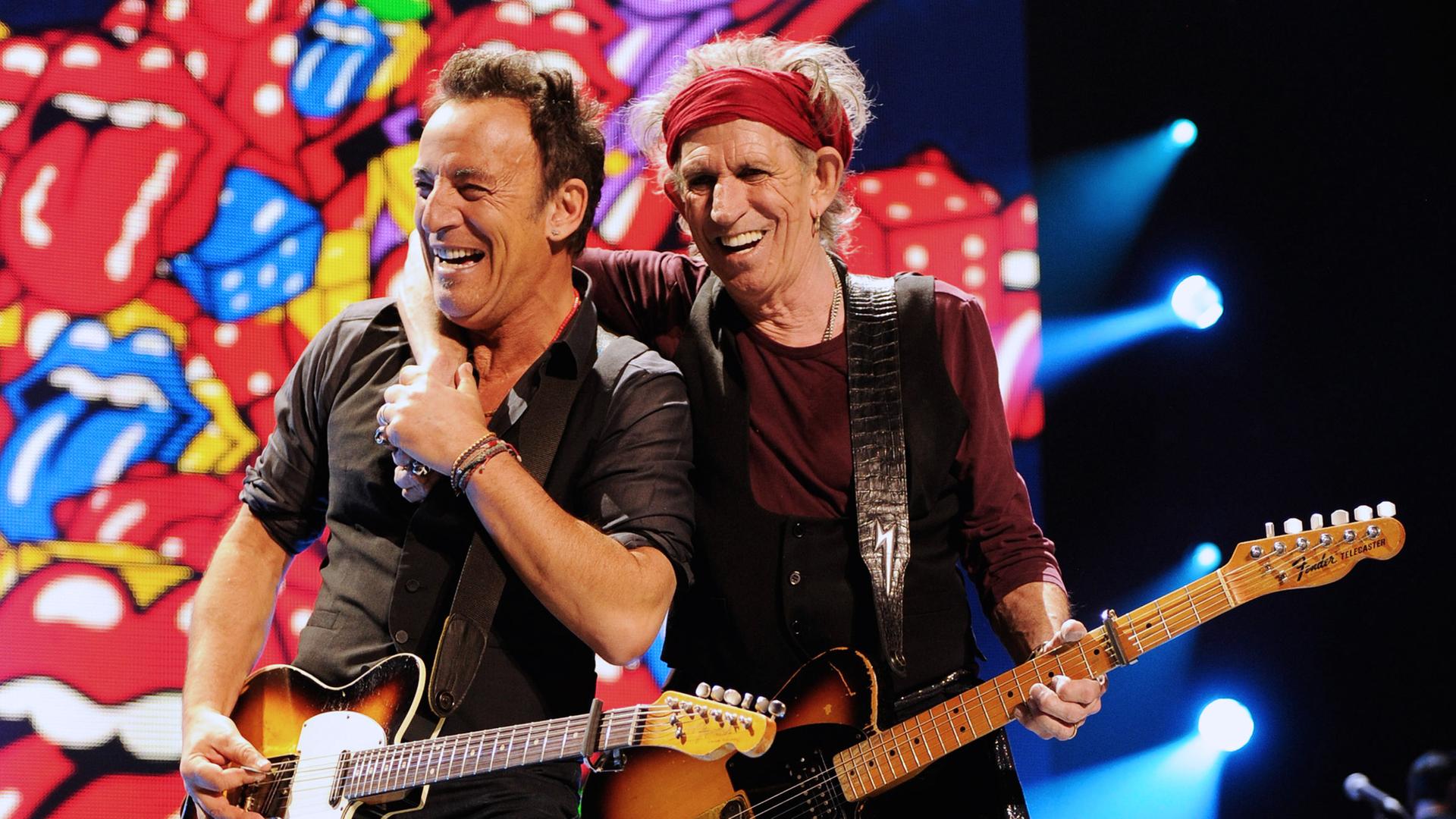 Bruce Springsteen und Keith Richards stehen mit ihren Gitarren auf der Bühne. Keith Richards legt den Arm um Bruce Springsteen.