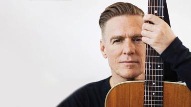 Nahporträt von Bryan Adams mit Gitarre.