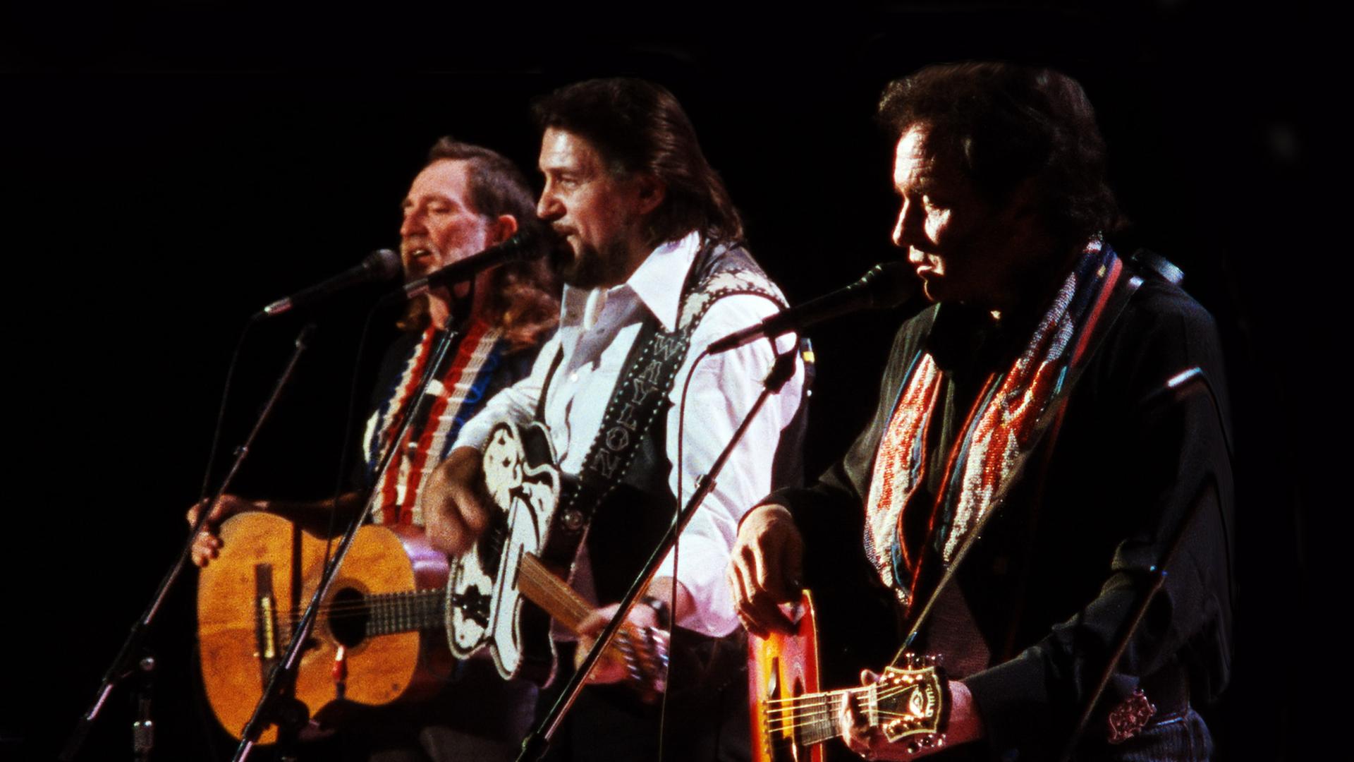 Die drei Mitglieder von The Highwaymen auf der Bühne, sie singen in Mikros.