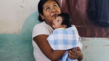 Eine Frau mit einem Baby auf dem Arm.