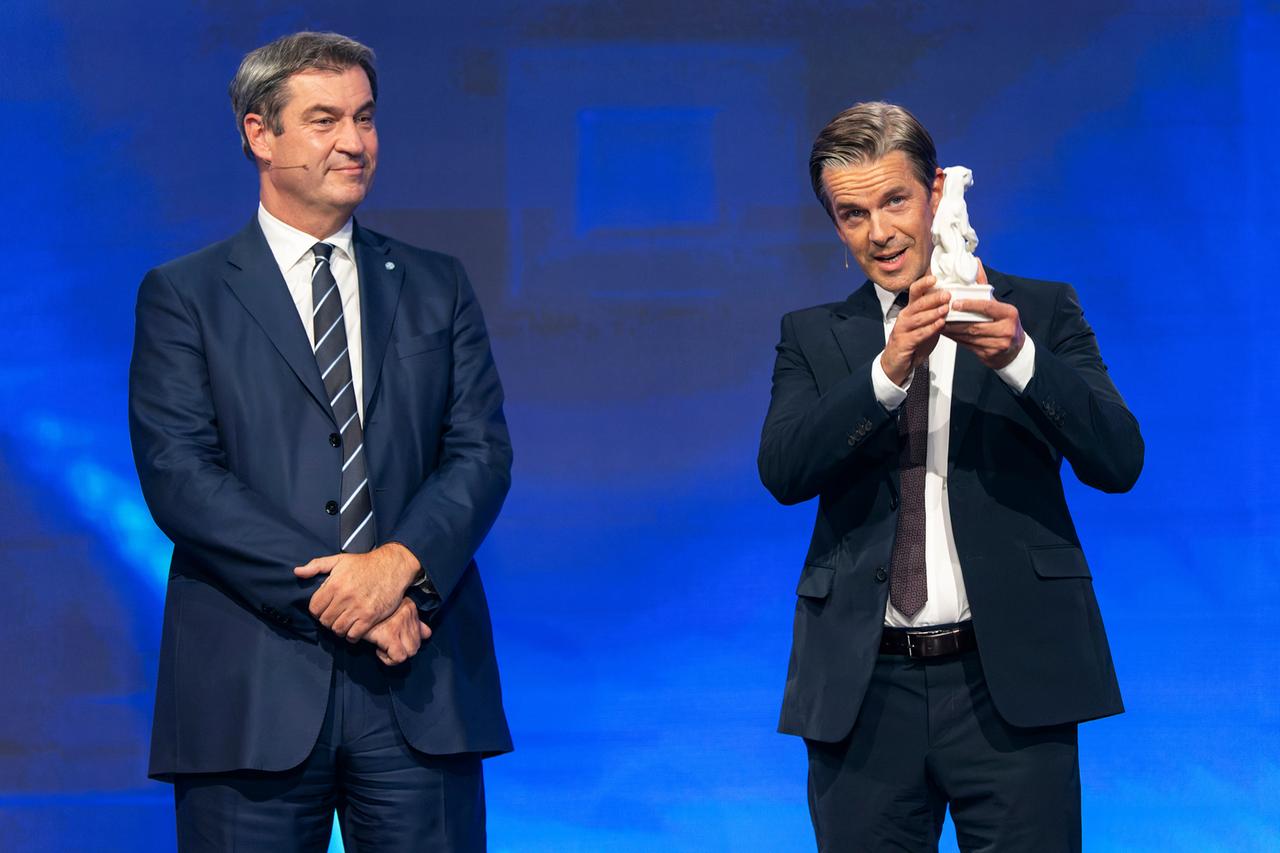Blauer Panther 2022: Markus Söder und Markus Lanz. Zwei Männer in dunklen Anzügen vor einem blau beleuchteten Hintergrund.