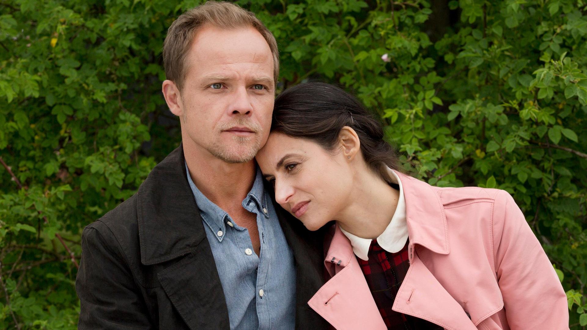 Eine Frau legt ihren Kopf auf die Schulter eines Mannes.