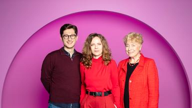 Sarah Bosetti steht in der Mitte des Bildes. Der Hintergrund ist rosa. Es sind drei Personen abgebildet. Links steht Philipp Türmer und rechts Gesine Schwan.