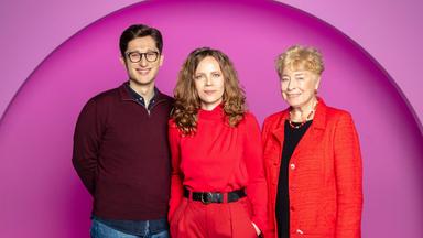 Sarah Bosetti steht in der Mitte des Bildes. Der Hintergrund ist rosa. Es sind drei Personen abgebildet. Links steht Philipp Türmer und rechts Gesine Schwan.