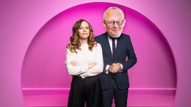 Auf dem Bild mit rosa Hintergrund sind zwei Personen abgebildet. Sarah Bosetti ist auf der linken Bildseite zu sehen. Sie trägt ein helles Oberteil und verschränkt die Arme vor der Brust.