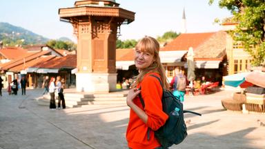 Eine blonde Frau auf einem Stadtplatz.