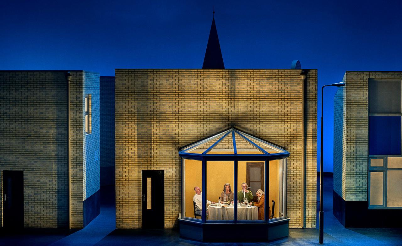 Vier Personen in einem gläsernen Erker auf einer Theaterbühne