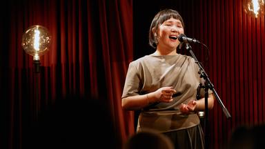 Eine Frau singt in ein Standmikrofon.