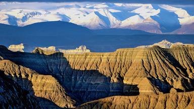 Steinfelsen vor schneebedecktem Gebirge