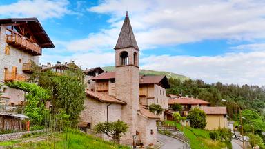 Ein malerisches Dorf in den Bergen mit Kirchturm.