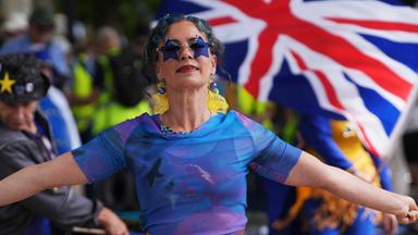 Bei einer Pro-Europäische-Union-Demo in Großbritannien tanzt eine in blaue Europafarben gekleidete und geschminkte Frau vor einem Union-Jack.