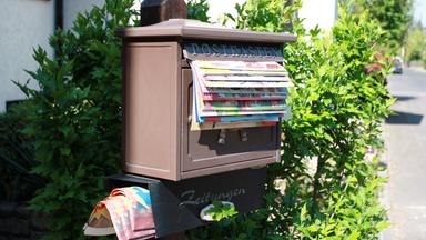 Briefkasten aus dem unzählige Prospekte herausragen.