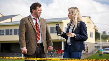 Ein Mann und eine Frau stehen auf einem Fußbaldfeld und blicken sich an.