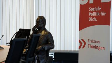Sitzende Statue von Willy Brandt in einem leeren Konferenzraum.