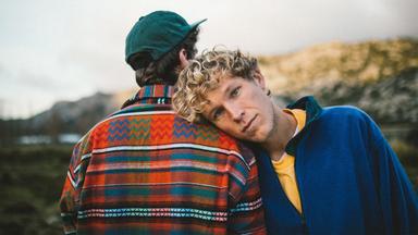 Close-Up der beiden Mitglieder der Band Bruckner, einer hat seinen Kopf auf die Schulter des anderen, der von hinten zu sehen ist, gelegt