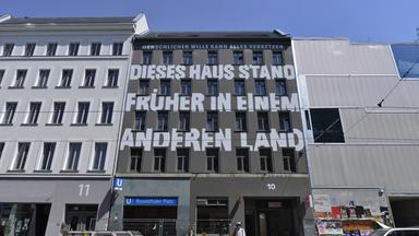 Aufschrift füllt die gesamte Front des Hauses aus: "Dieses Haus stand früher in einem anderen Land"