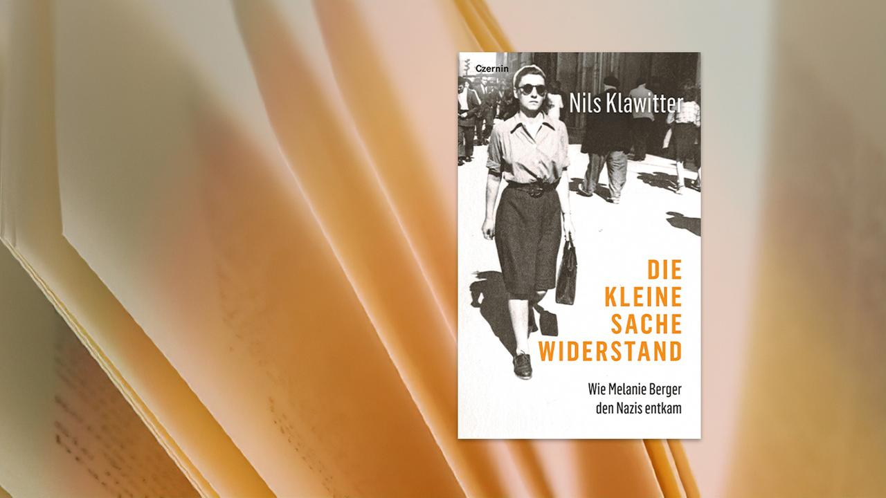 Straßenszene: Eine Frau, gekleidet mit einem knielangem Rock und Bluse, trägt Sonnenbrille und eine Tasche. Hinter ihr sind Menschen zu sehen.