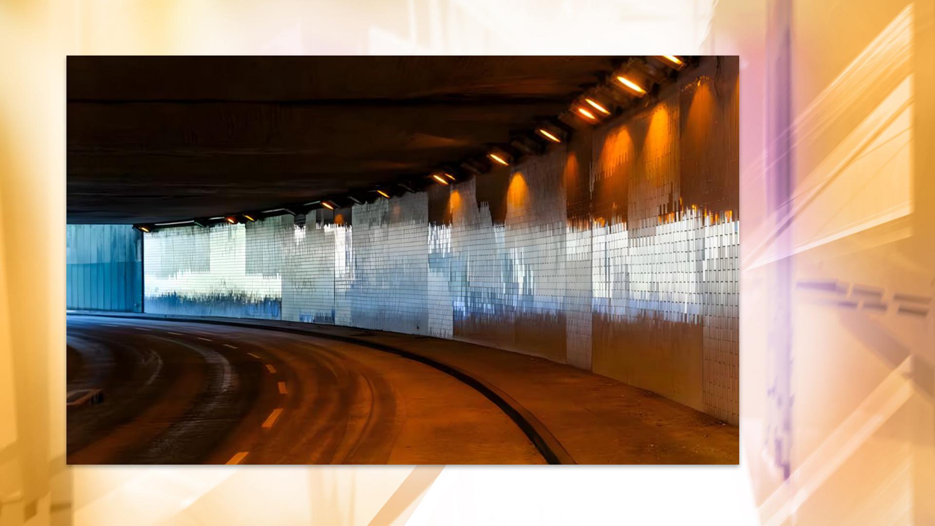 Ein gekachelter und beleuchteter Autobahntunnel von innen.