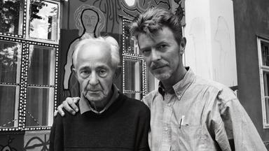 Schwarz-weiß-Foto eines jüngeren Mannes, der einem älteren Mann den Arm um die Schulter legt.