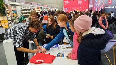Kinder lassen sich ein T-Shirt unterschreiben