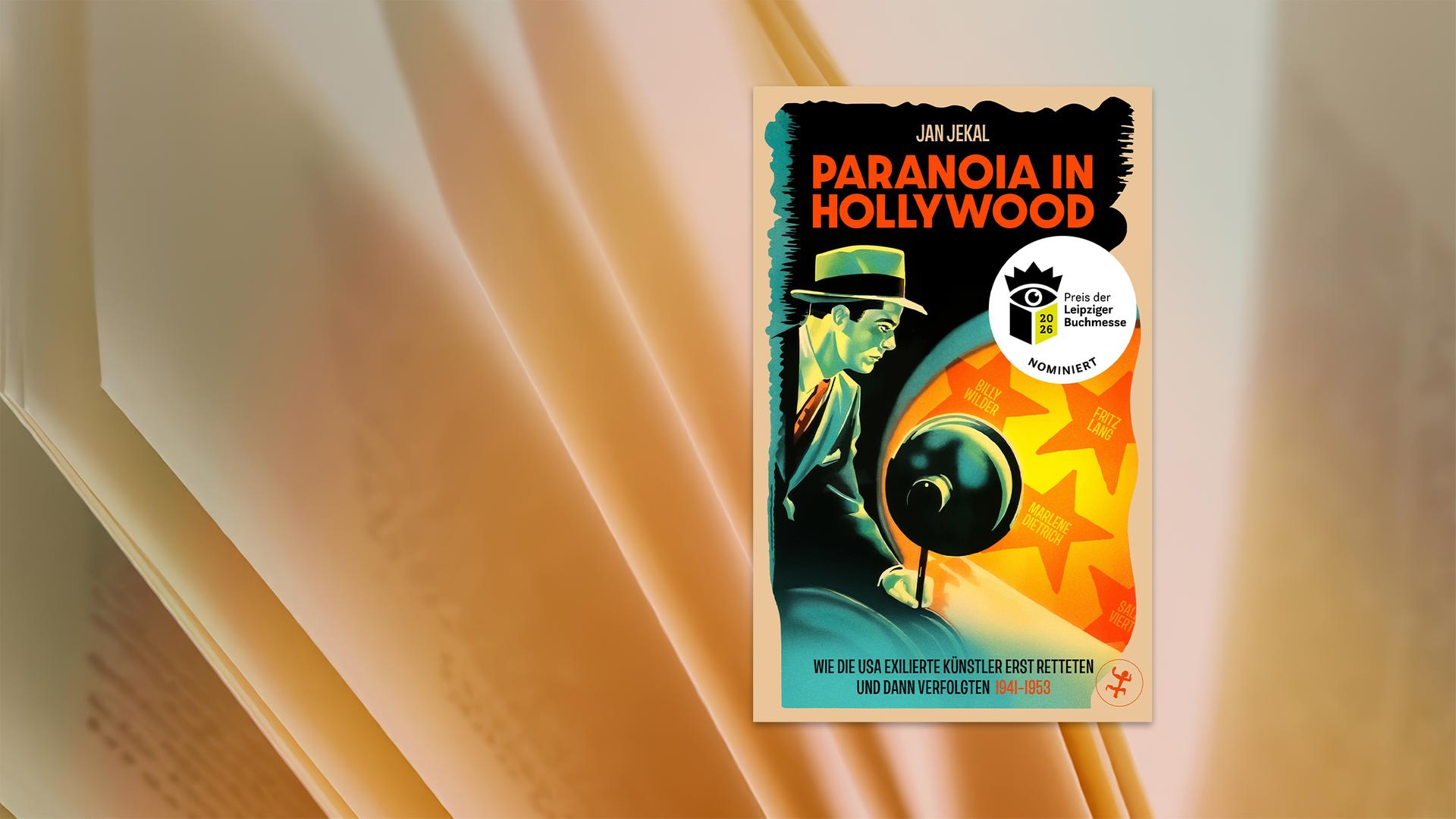 Ein Mann in Anzug und mit Hut, der eine Lampe hält und damit auf eine Wand leuchtet. Dort sind Sterne wie beim Hollywood Walk of Fame zu sehen.