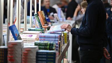 Um einen Büchertisch stehen mehrere Personen und schmökern.