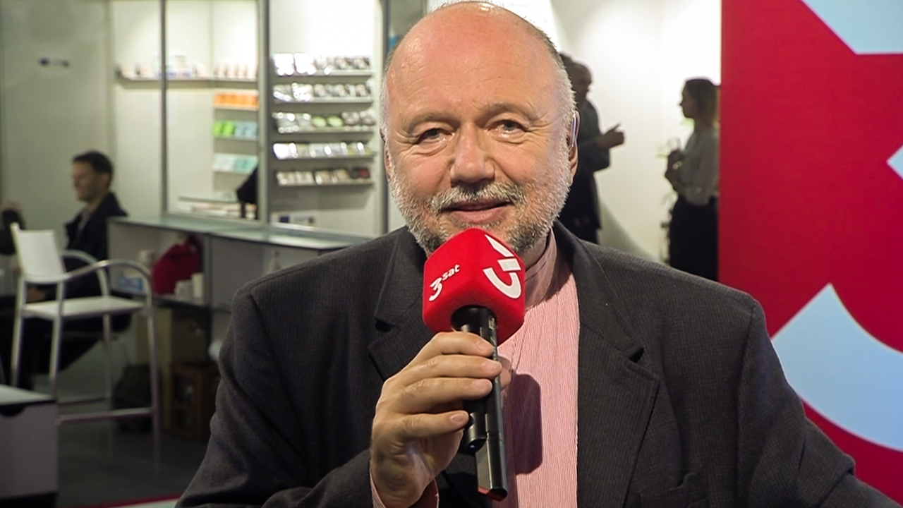 Ein Mann auf der Buchmesse am Mikrofon