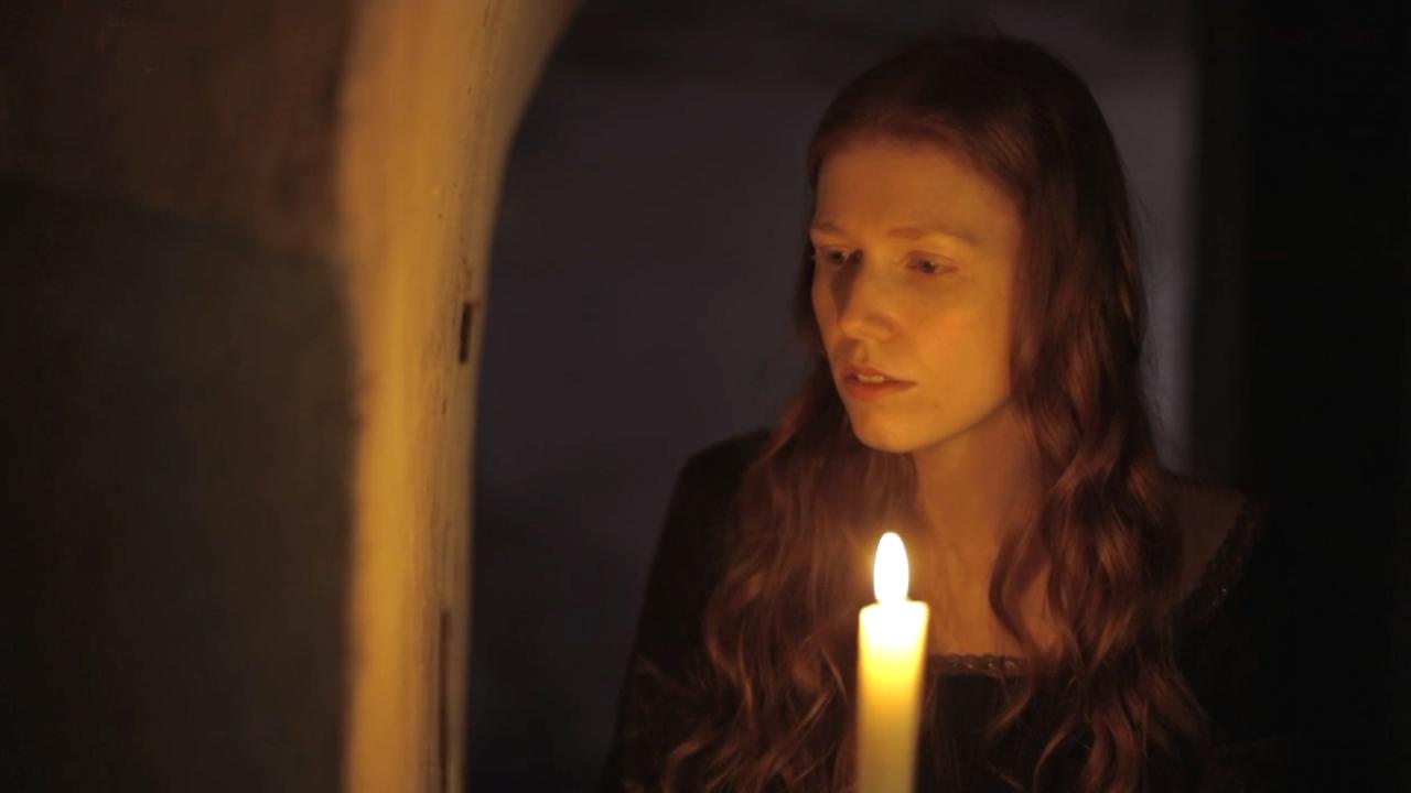 Szene aus "Porträt einer Ehe" von Maggie O´Farrell: Eine junge Frau steht in einem Gang aus dickem Gemäuer und hält eine Kerze in der Hand.