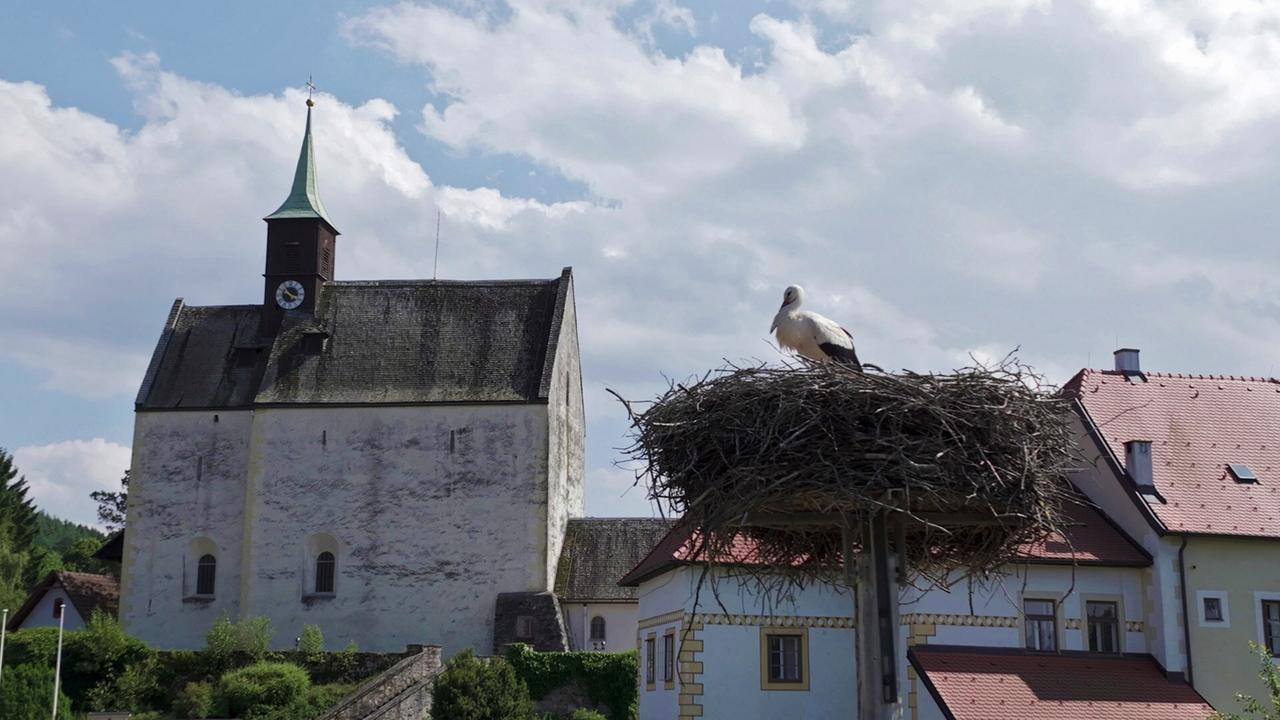 Eine kleine Kirche mit einem Storchennest im Vordergrund