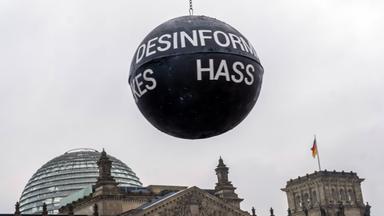 Ballon mit Aufschrift Deepfake schwebt über dem Bundestagsgebäude