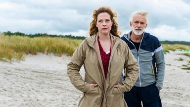 Camping-Kalle (Christoph M. Ohrt) steht hinter Desiree (Diana Amft) am Strand.