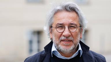 Foto eines Mannes mit weißen Locken, graumeliertem Bart und runder Metall-Brille.