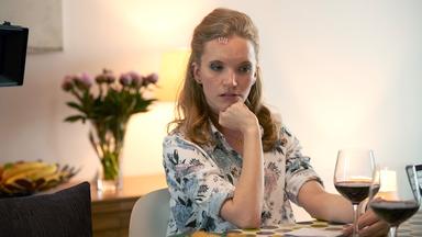 "Cecelia Ahern: In deinem Leben - Teil 1": Joyce sitzt an einem Tisch und schaut nachdenklich auf die Tischdecke vor ihr. Vor ihr steht ein halb gefülltes Rotweinglas, sie hat den rechten Ellbogen auf den Tisch gestützt und die Hand zu einer Faust gemacht, mit der sie das Kinn stützt.