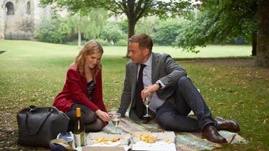 "Cecelia Ahern: In deinem Leben - Teil 2": Joyce und Justin sitzen in einem Park auf einer Decke und machen ein Picknick. Vor ihnen Essensreste auf Pappverpackung, eine Weißweinflasche und Gläser.