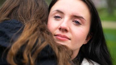 Laura schaut Richtung Kamera und umarmt Poppy.