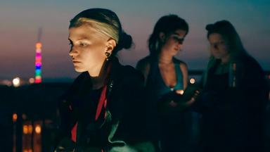 Drei junge Mädchen auf einem Hausdach.