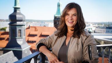 Eine Frau lehnt an einem Turmgeländer.