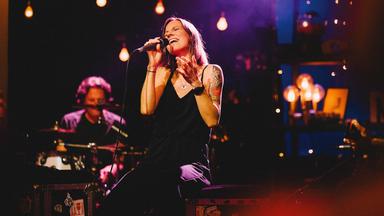 Christina Stürmer singt in ein Mikrofon. Hinter ihr ist ihre Band zu sehen.