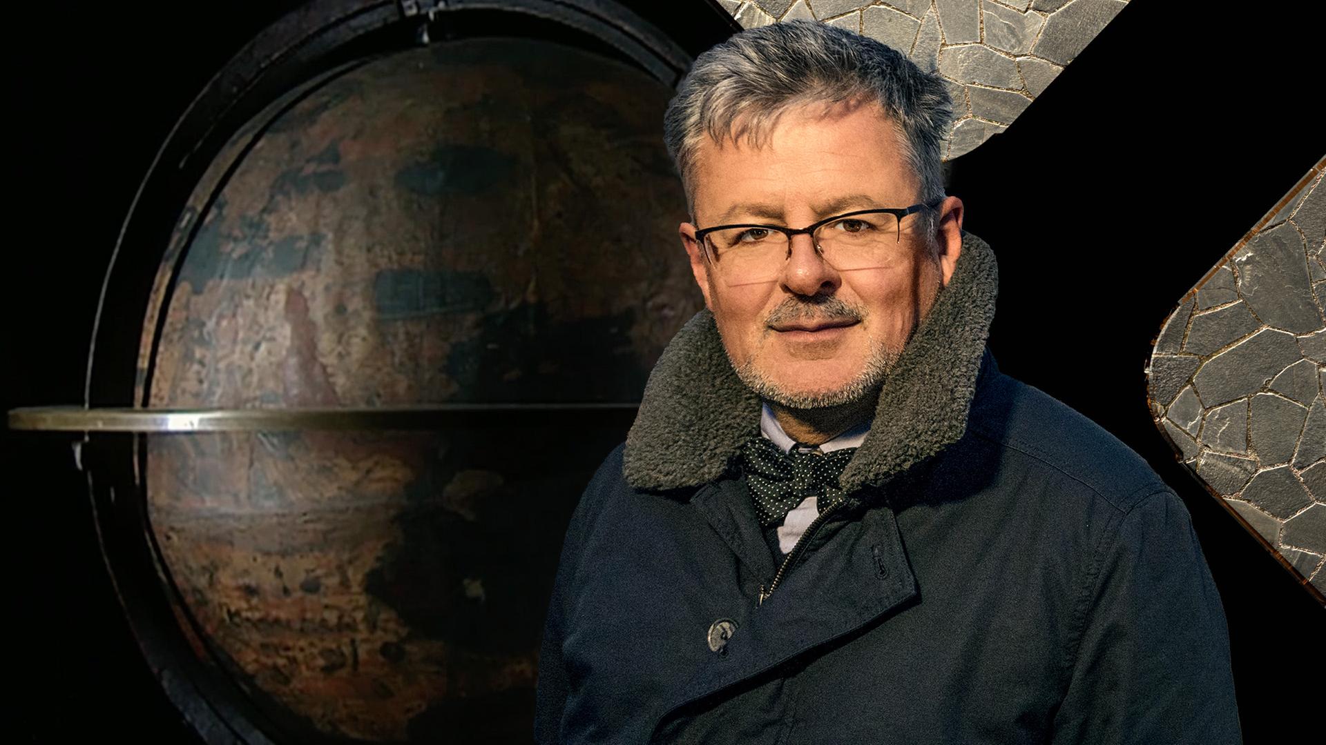 Christopher Clark steht vor einem Globus