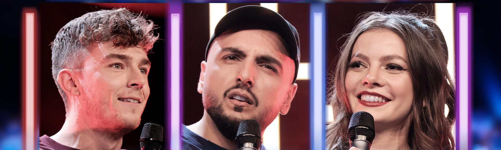 Auf dem Bild sind die Comedians Hendrik Brehmer, Sezer Oglu und Maria Clara Groppler zu sehen. Sie halten ein Mikrofon in der Hand und stehen auf einer Bühne
