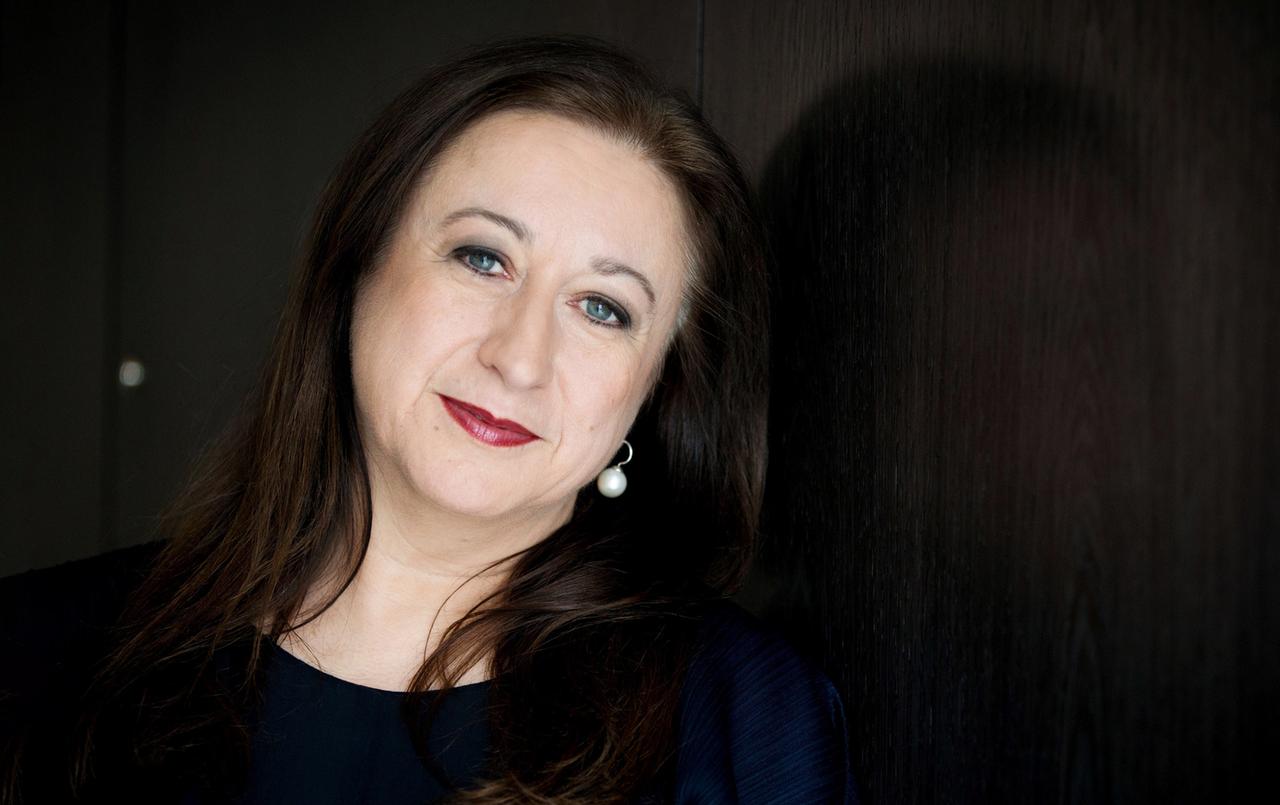 Ein Porträt von einer lächelnden Frau vor dunklem Hintergrund