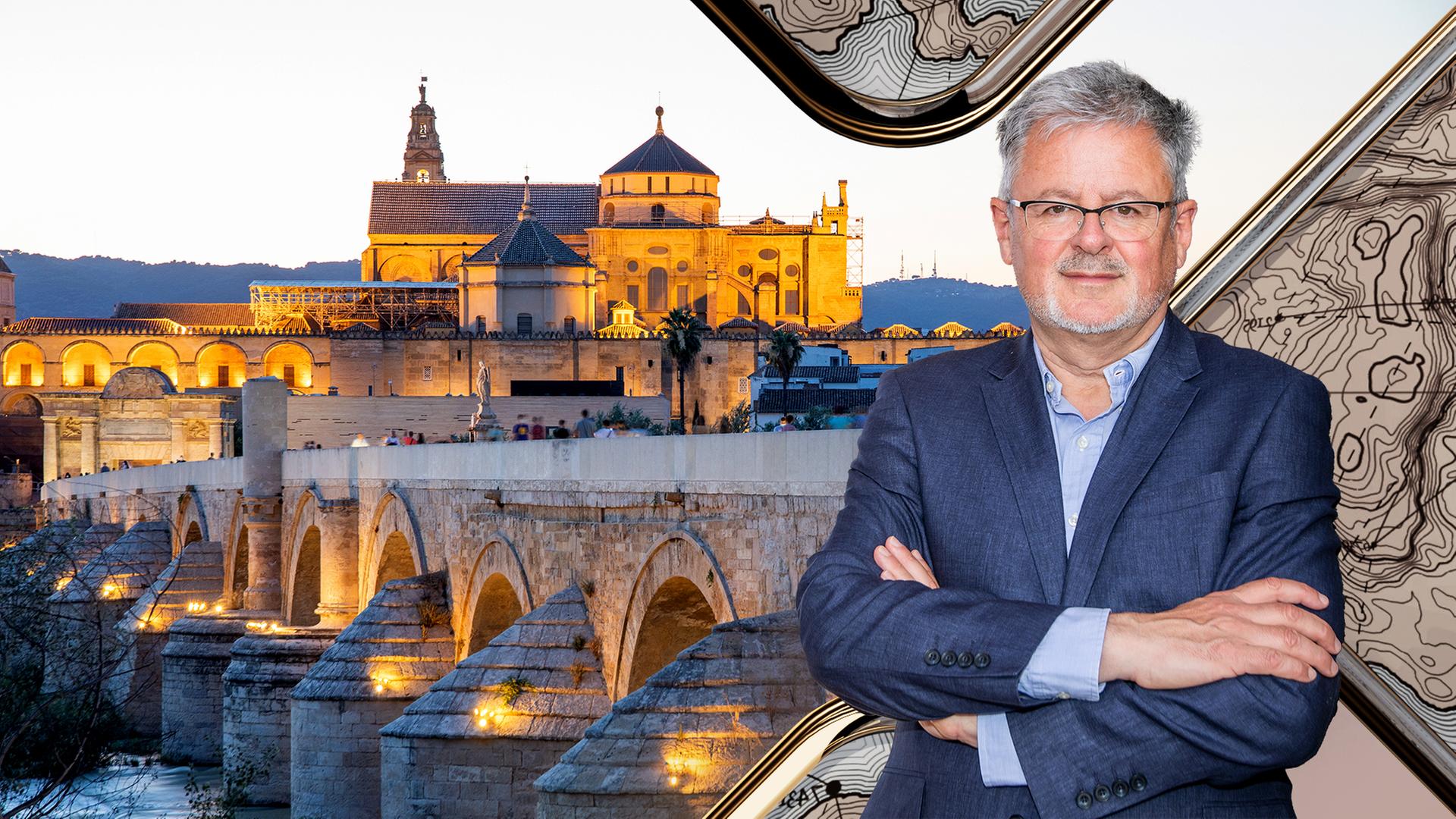 Blick auf die bei Dämmerung beleuchtete Römische Brücke in Cordoba mit ihren schönen Torbögen und der dahinterliegenden Altstadt. Rechts im Vordergrund Christopher Clark.